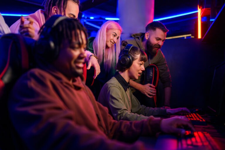 Focused interracial gamers playing online battle while friends w